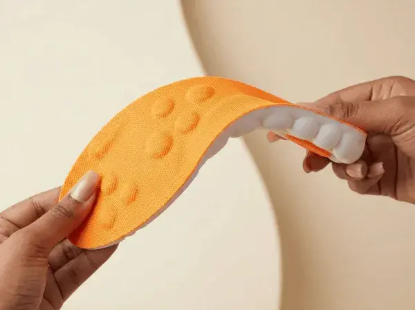Hands bending orange Stepprs insole to show flexibility and build quality